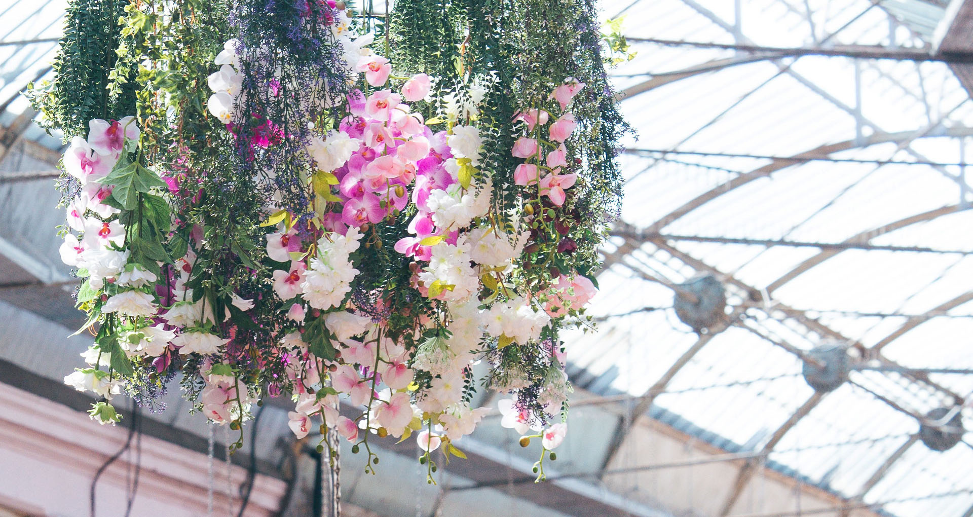 A hanging flower basket within a covered shopping arcade.