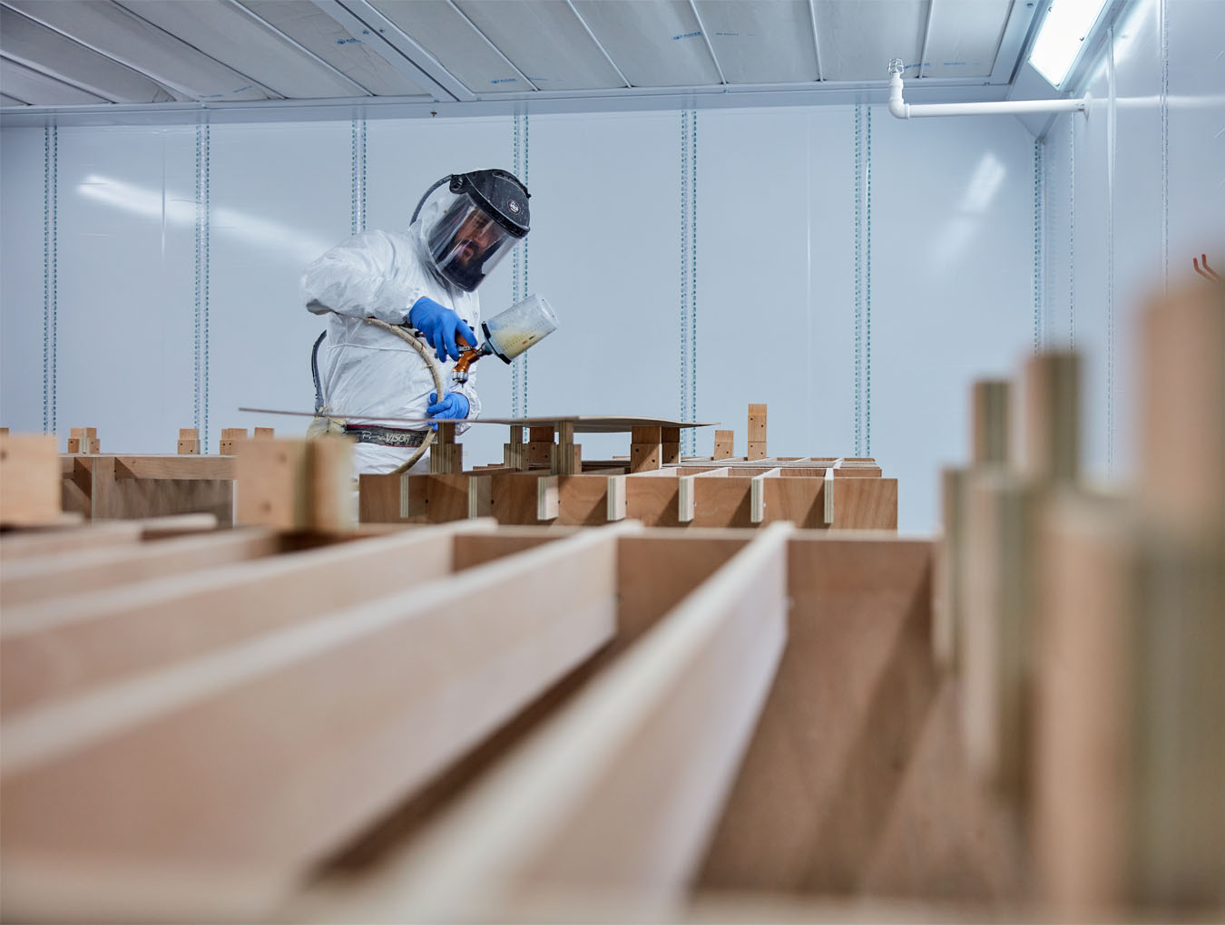 Man in mask spray painting a metal sheet